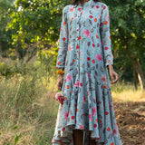 Woman wearing a floral dress standing in a natural setting with trees and grass.