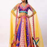 A woman modeling a traditional Indian lehenga set with a multicolored kali lehenga and an organza dupatta in yellow, featuring hand embroidered details and sequence work.