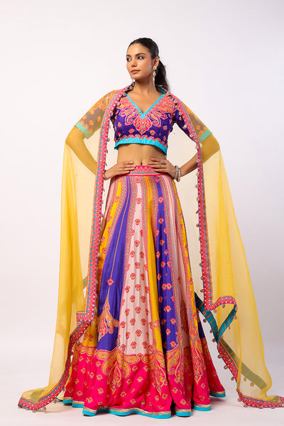 A woman modeling a traditional Indian lehenga set with a multicolored kali lehenga and an organza dupatta in yellow, featuring hand embroidered details and sequence work.