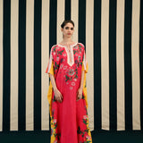 A woman standing against a striped background, wearing a fuchsia-colored kaftan with floral embroidery and a side slit, paired with a yellow dupatta with floral patterns.