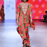 A model walking down a runway showcasing a multicolored Gulal Square Poncho with Sharara set, featuring intricate hand embroidery and a flared design.