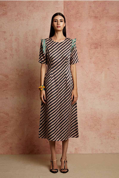 A model wearing a black and beige striped fitted dress with pleated detailing on the armholes and back, paired with yellow earrings.